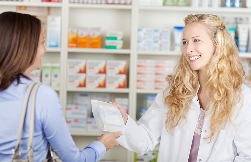Una farmac&eacute;utica entrega un paquete con medicinas a una clienta